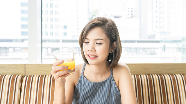 Asian woman drinking an orange juice in the restaurant