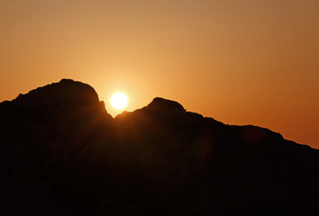 landscape with sun rising between two rocks