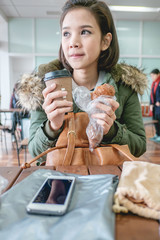 Asian woman holding a cup of coffee and a croissant