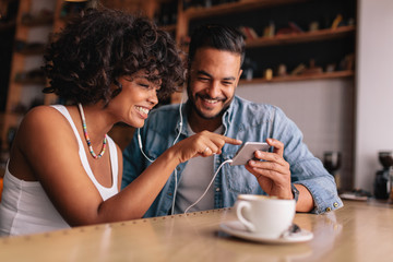 Smiling couple at cafe using smart phone