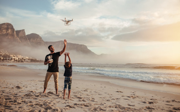 Father and son flying drone with remote control at beach