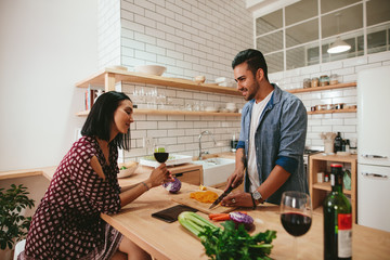 Young couple talking while cooking in kitchen