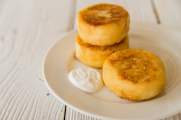 Cottage cheese cakes on plate with sour cream