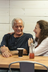 Fototapeta na wymiar Smiling happy elderly couple have a coffe in a bar
