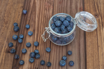 Blueberries in a jar on a wooden table.