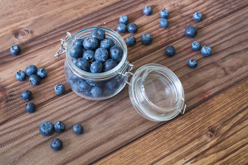 Blueberries in a jar on a wooden table.