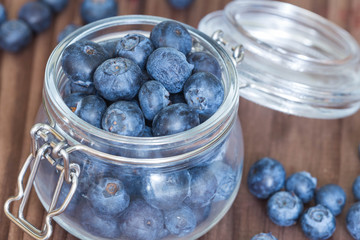 Blueberries in a jar on a wooden table.