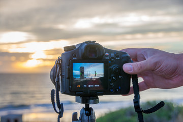 Mann bedient eine Kamera, um den Sonnenuntergang zu fotografieren - obrazy, fototapety, plakaty
