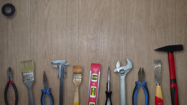 Different tools moving on wooden background. Hammer, screwdriver, pliers, brushes and over equipment fly from top of the screen to the bottom. With place for text. Animation based on real photos. 