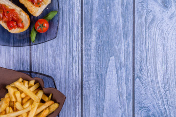 Italian bruschetta, a grilled crusty bread with tomatoes in pieces, basil and mozzarella cheese and a plate of french fries