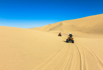 Fototapeta na wymiar Quad driving people - two happy bikers in sand desert.