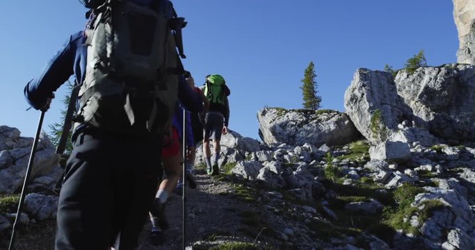 Four friends walking along hiking trail path. Group of friends people summer adventure journey in mountain nature outdoors. Travel exploring Alps, Dolomites, Italy. 4k slow motion 60p video