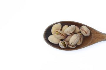 Pistachio nuts in wooden spoon isolated on white background.