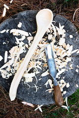 Wooden handmade spoon with wood carving tool and shavings
