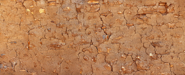 Grunge stone wall covered with clay plaster. Vintage architectural background