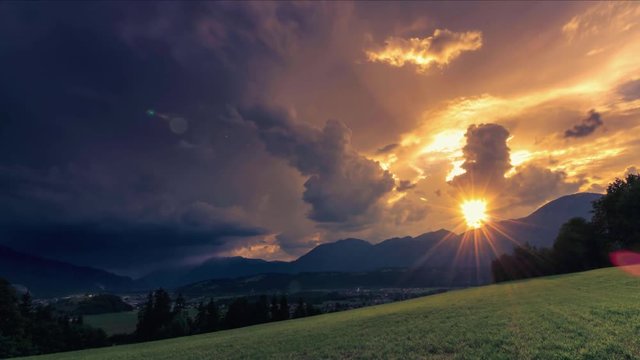 4K. Timelapse of dramatic sunset after hot day in summer with sunrays and flying clouds over Alps of Austria, Europe. Massive storm coming. 