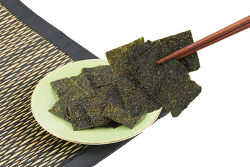 Sheet of dried crispy seaweed in chopsticks and dish isolated on white background - clipping paths