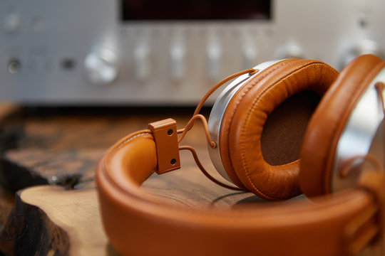 Vintage Headphones lie on a wooden table. Background amplifier hifi
