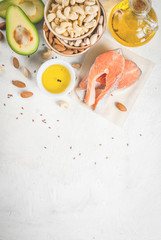 Healthy food. Products with healthy fats. Omega 3, omega 6. Ingredients and products: trout (salmon), flaxseed oil, avocado, almonds, cashews, pistachios. On a white stone table. Copy space top view