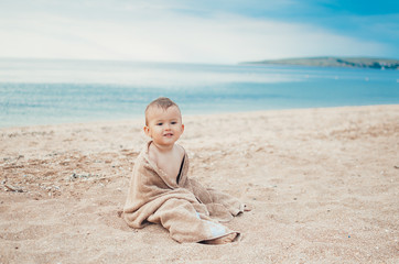 adorable little boy in a yellow towel on the beach