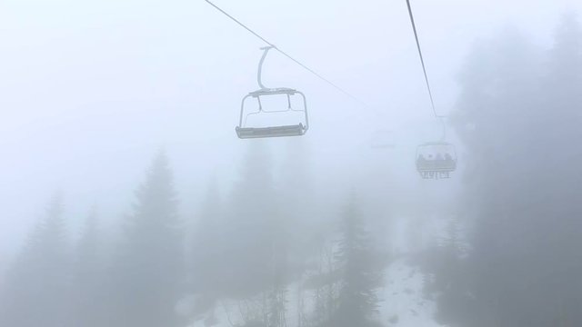 Tourists go in cabins on the ropeway through fog. Early morning trip above misty forest in Mestia, Georgia.
