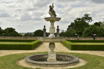 Fototapeta na wymiar La fontaine rustique et circulaire au milieu du jardin à la française au domaine du château de Gaasbeek près de Bruxelles
