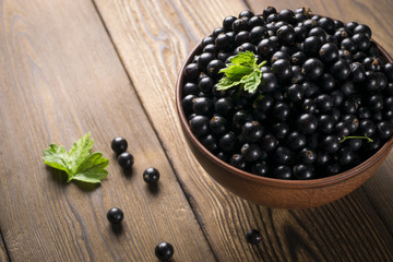 Black currant on wooden table with leaf sprig