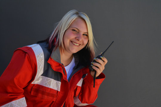 Junge l&auml;chelnde Frau mit Rettungssanit&auml;ter Jacke und Walkie-Talkie