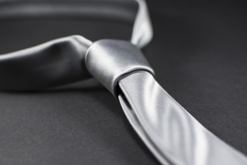Beautiful silver necktie isolated on black background. Close up of a fashionable men's accessory.