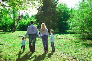 Naklejka na ściany i meble A family of four walks in the park.