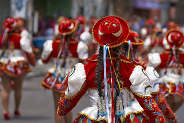 Caporales dance group in ornate red and white costumes performing at the annual Carnaval Andino con la Fuerza del Sol in Arica, Chile.