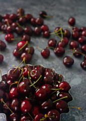 Fresh organic cherries in metal bowl on dark stone background, healthy seasonal food, diet, tasty berries, selective focus