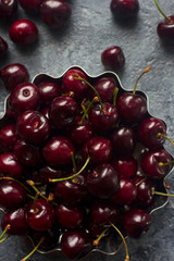 Fresh organic cherries in metal bowl on dark stone background, healthy seasonal food, diet, tasty berries, top view, selective focus