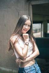 A beautiful girl with long hair in white shirt and jeans, standing poses on train vintage style