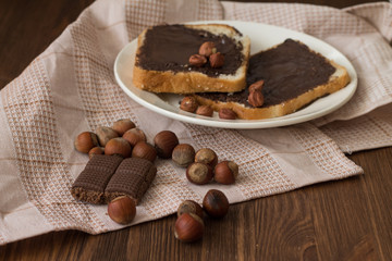 toast with peanut butter on a plate on the table with hazelnuts