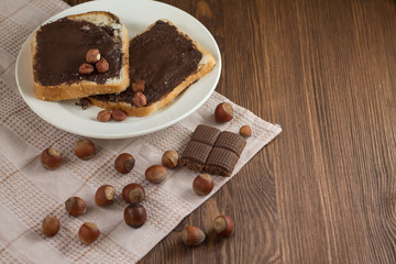 toast with peanut butter on a plate on the table with hazelnuts