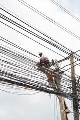 Electricians are replacing the mains cable on the high voltage poles