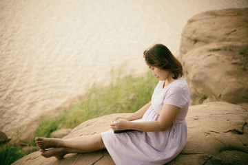 Happy beautiful pregnant woman read  book on the rock side dam vintage style,sepia tone,dark,film