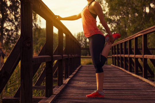 Sportliche Frau dehnt sich an einer Br&uuml;cke nach dem Training