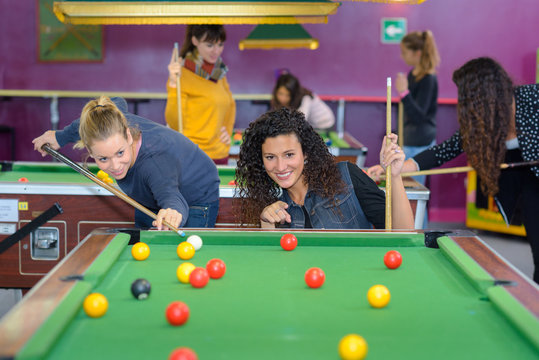 beautiful smiling women playing billiards at a bar