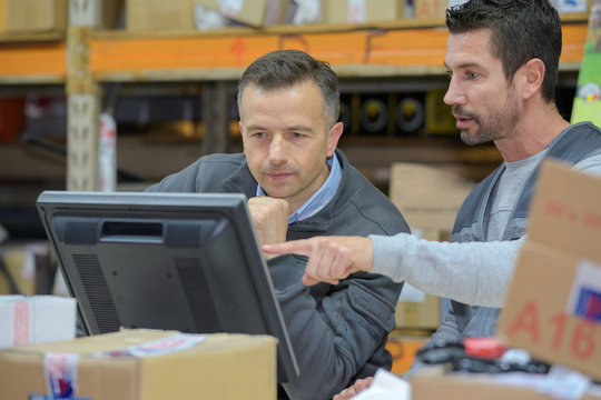 Warehouse Worker And Manager Using Computer In A Warehouse