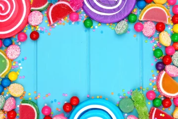 Afwasbaar Fotobehang Snoepjes Frame of assorted colorful candies against a blue wood background