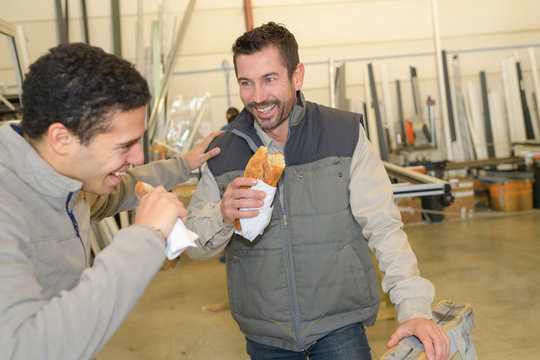 cheerful workers having lunch eating sandwich in a workshop
