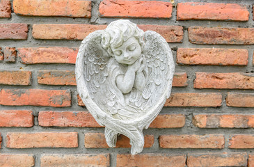 Little angle statue on brick wall