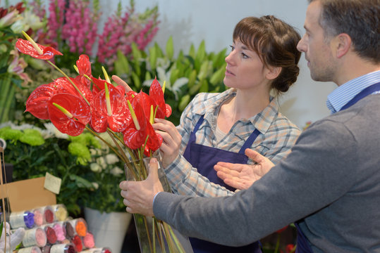 female florists assisting male customer in buying flower