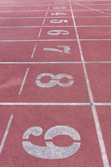 White Number athletic track number on red rubber racetrack, texture of running racetracks in stadium
