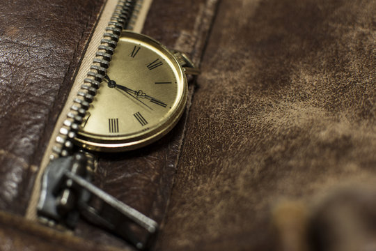 Close up of a beautiful pocket watch. Luxury men's watch placed on a leather background. Fashionable brown leather bag with a watch on top of it.