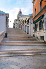 Fototapeta na wymiar Venice, Italy, May, 31, 2017: empty street at sunrise in Venice, Italy, There are steps of a bridge staircase on a frontground