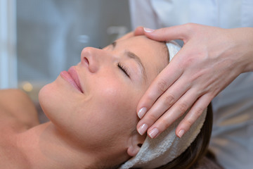 Obraz na płótnie Canvas beautiful young woman receiving facial massage