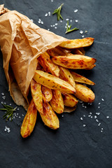 Baked potato fries with addition  sea salt and rosemary on a black background, top view